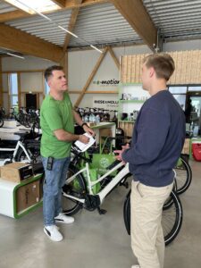 Zwei Männer stehen neben Betreuungsrädern in einem E-Bike-Weltladen.